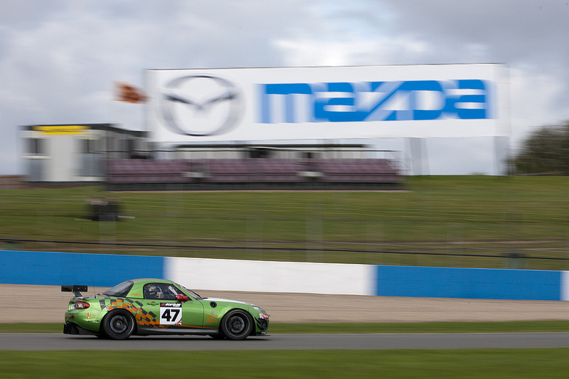 The Jota Mazda MX-5 races past a Mazda sign at Donington