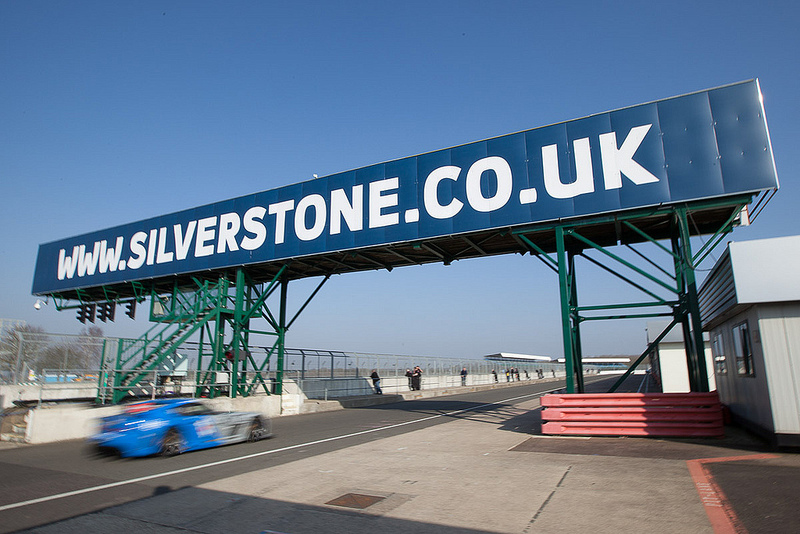 The Silverstone starting gantry with a car racing under it - Silverstone Photography