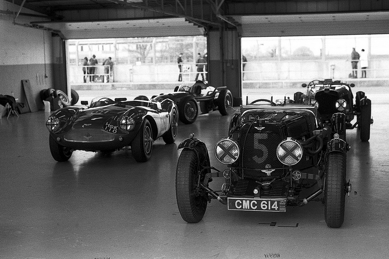Two Aston's in the pits at silverstone in black and white.