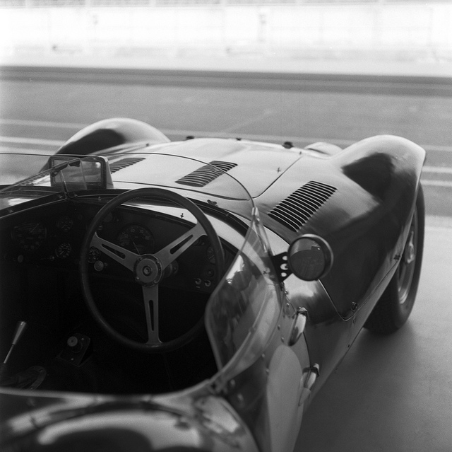 A 1950s sportscar in the pits at silverstone, in black and white.
