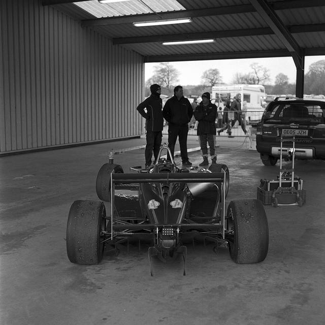 An F3 car at Oulton Park with blokes stood in the distance.